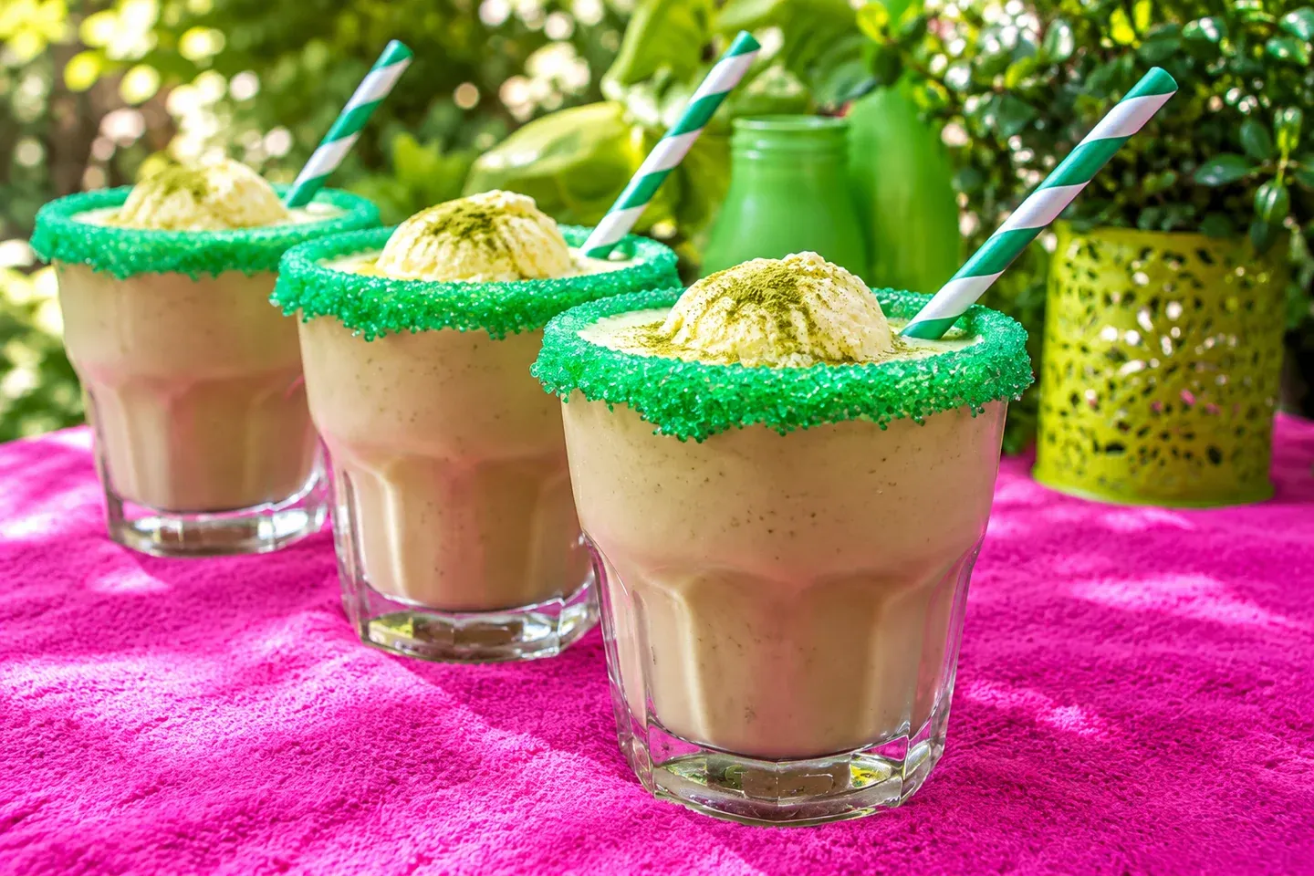 Three matcha ice cream smoothies with green sugar rims and vanilla ice cream